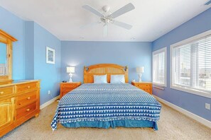 A bedroom with a bed, wooden nightstands, a ceiling fan, and a window with blinds. - Key Largo Penthouse w/ Ocean View, W/D, WiFi, AC - Half a Block to the Beach (Ocean City)