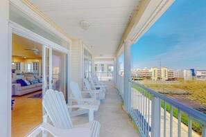A covered balcony with white Adirondack chairs, a view of the cityscape, and a glimpse of the interior with a sofa and a ceiling fan. - Key Largo Penthouse w/ Ocean View, W/D, WiFi, AC - Half a Block to the Beach (Ocean City)