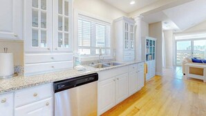 A modern kitchen with white cabinetry, a dishwasher, and a large window. - Key Largo Penthouse w/ Ocean View, W/D, WiFi, AC - Half a Block to the Beach (Ocean City)