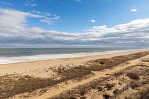 Une plage avec un sentier de sable, une clôture et une vue dégagée sur l’océan.