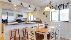 Una cucina con mobili bianchi, un'isola centrale e un'area pranzo con sedie bianche.