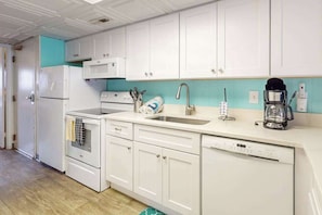 A kitchen with white cabinets, a sink, a stove, and a coffee maker. - Ocean-view condo with balcony & pool access - steps from the beach (Ocean City)