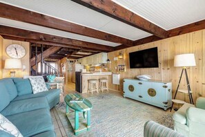 Ein gemütliches Wohnzimmer mit einer Couch, einem Couchtisch, einem Fernseher und einer Küchenzeile im Hintergrund.