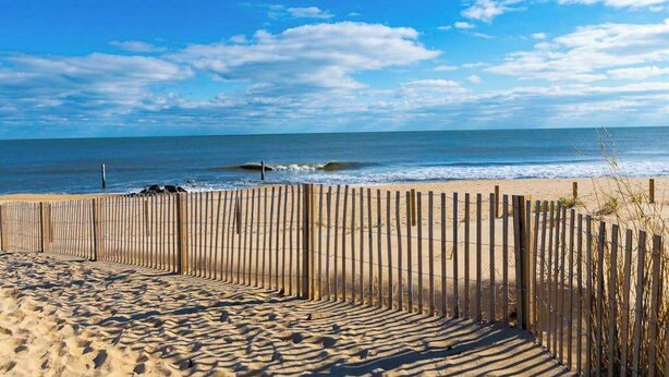 A beach with a wooden fence, sandy beach, and ocean waves. - Adagio 407 (Ocean City)