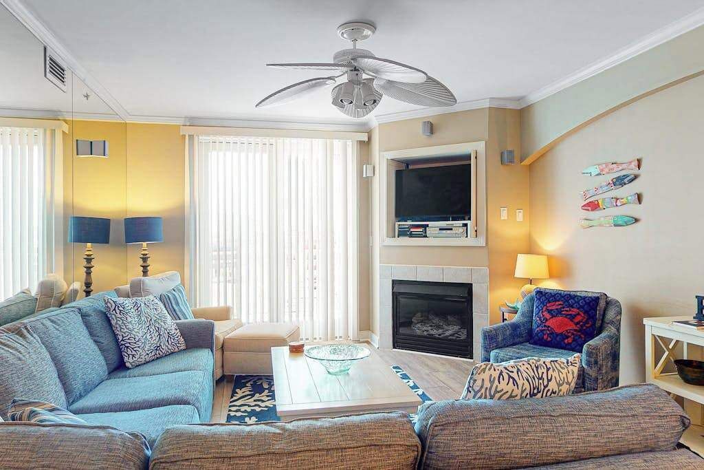 A living room with a sofa, armchair, coffee table, fireplace, television, and decorative items.