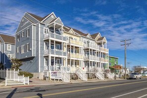 A multi-story residential building with balconies, a gated driveway, and a clear sky. - Saint Louis Ave townhouse central AC & private washer/dryer - near the ocean (Ocean City)