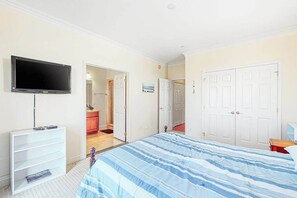 A bedroom with a bed, a TV, a dresser, and a closet.