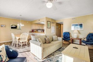 A living room with a sofa, chairs, a coffee table, and a dining area with a table and chairs. - Inviting top-floor condo with amazing ocean views, large balcony, & fast WiFi (Ocean City)