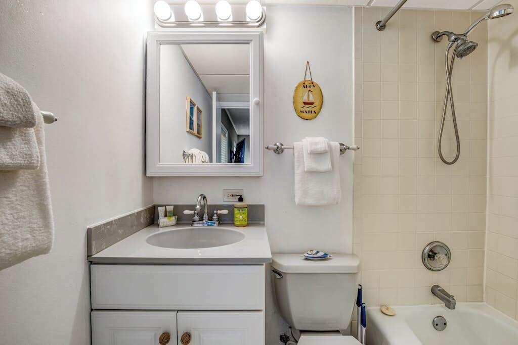 Ein Badezimmer mit Waschbecken, Spiegel, Handtuchhalter, Toilette und Dusche.