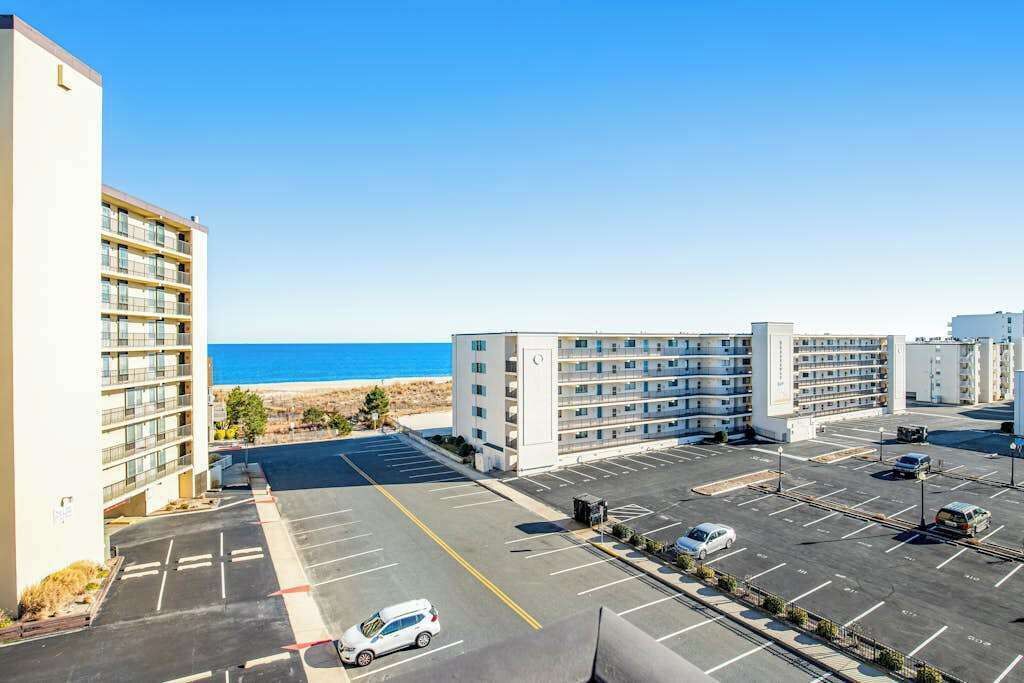 A multi-story hotel with a parking lot and a view of the beach.