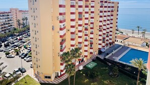 A high-rise hotel with multiple balconies, a swimming pool, and a view of the beach. - Apartamento Faro 77 by At Home Costa del Sol (Torrox)