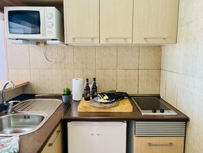 A compact kitchen with a microwave, sink, and a small refrigerator. - Apartamento Faro 77 by At Home Costa del Sol (Torrox)