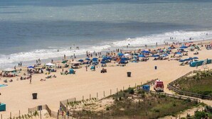 A beach with umbrellas, people, and a lifeguard tower. - Irene 1106 (Ocean City)
