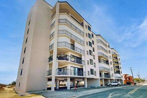 A multi-story residential building with balconies, a parking area, and a clear sky. - Fourth-Floor Condo near the Beach w/Private Balcony, Ocean View, A/C, Free WiFi (Ocean City)
