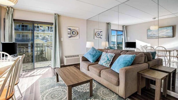 A modern living room with a sofa, coffee table, and dining area. - Decatur House 203 (Ocean City)
