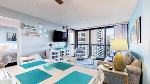 A modern living room with a dining area, a TV, and a sofa. - Colorful, ocean-view condo with scenic balcony, 3 pools, washer/dryer & AC (Ocean City)