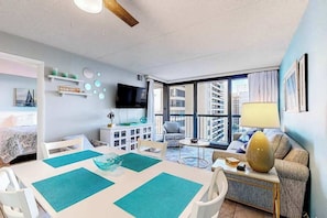 A modern living room with a dining area, a TV, and a sofa. - Colorful, ocean-view condo with scenic balcony, 3 pools, washer/dryer & AC (Ocean City)