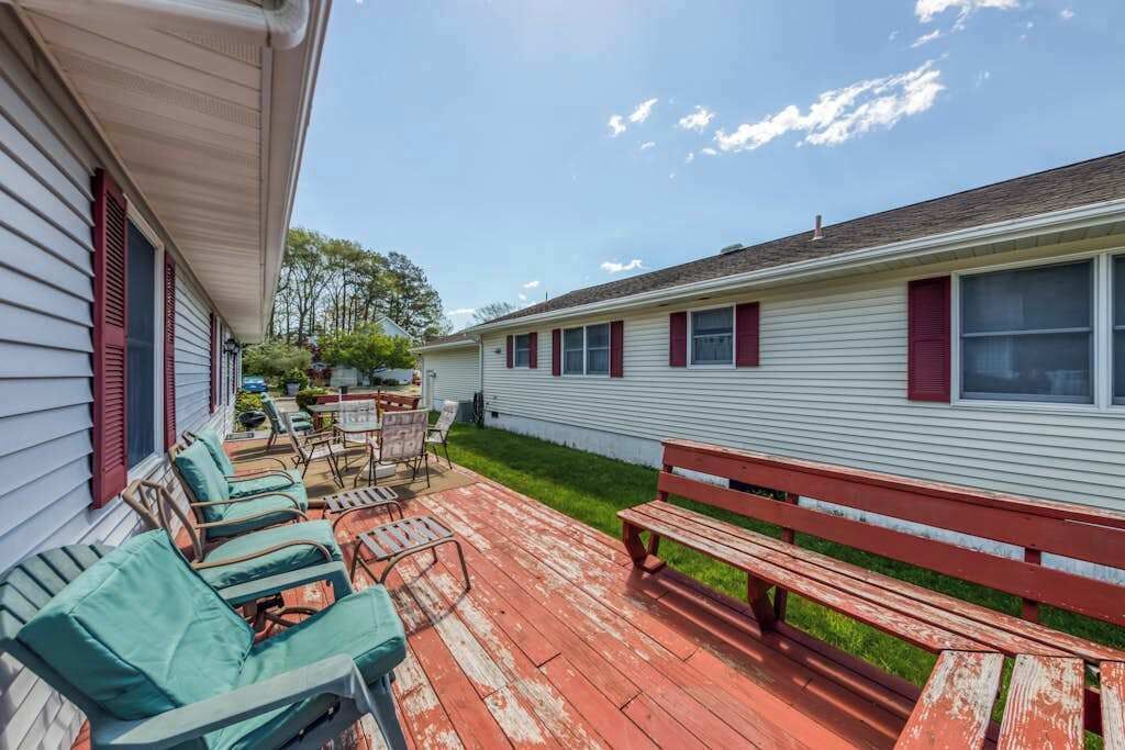 A covered patio with outdoor furniture, a bench, and a small table.