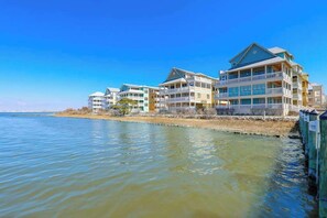 Ein Hotel am Wasserufer mit mehreren Balkonen, freiem Blick auf das Wasser und einer flachen Dachkonstruktion.