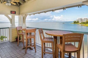 A covered outdoor seating area with a view of a body of water and buildings in the distance. - Spacious Townhome w/ Bay Views & WiFi - Walk to Resort Pools/Beaches (Ocean City)