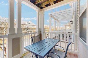 A covered outdoor area with a table and chairs, white railings, and a view of the surrounding neighborhood. - Spacious Townhome w/ Bay Views & WiFi - Walk to Resort Pools/Beaches (Ocean City)