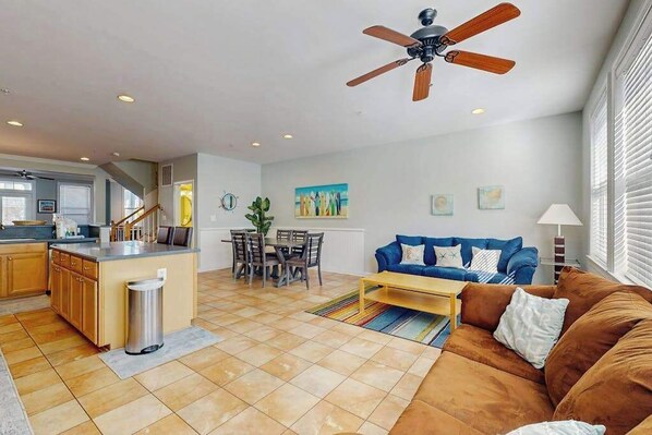 A spacious living area with a kitchen, dining table, and a blue sofa. - Spacious Townhome w/ Bay Views & WiFi - Walk to Resort Pools/Beaches (Ocean City)