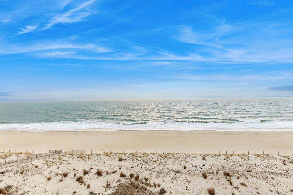 Ein Strand mit einem Zaun im Vordergrund und dem Meer im Hintergrund.