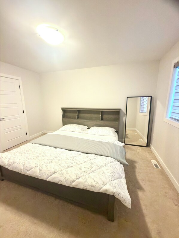 Um quarto com cama, espelho, porta e janela.