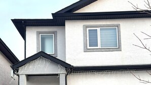 A two-story building with a front entrance, a red door, and a small porch area. - Spacious 3BR Family Home | 2 King Beds & queen bed,Big Deck & Garage & free wifi (Winnipeg)