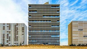 Un immeuble à plusieurs étages doté d’une architecture moderne, caractérisée par des lignes horizontales et un toit plat.