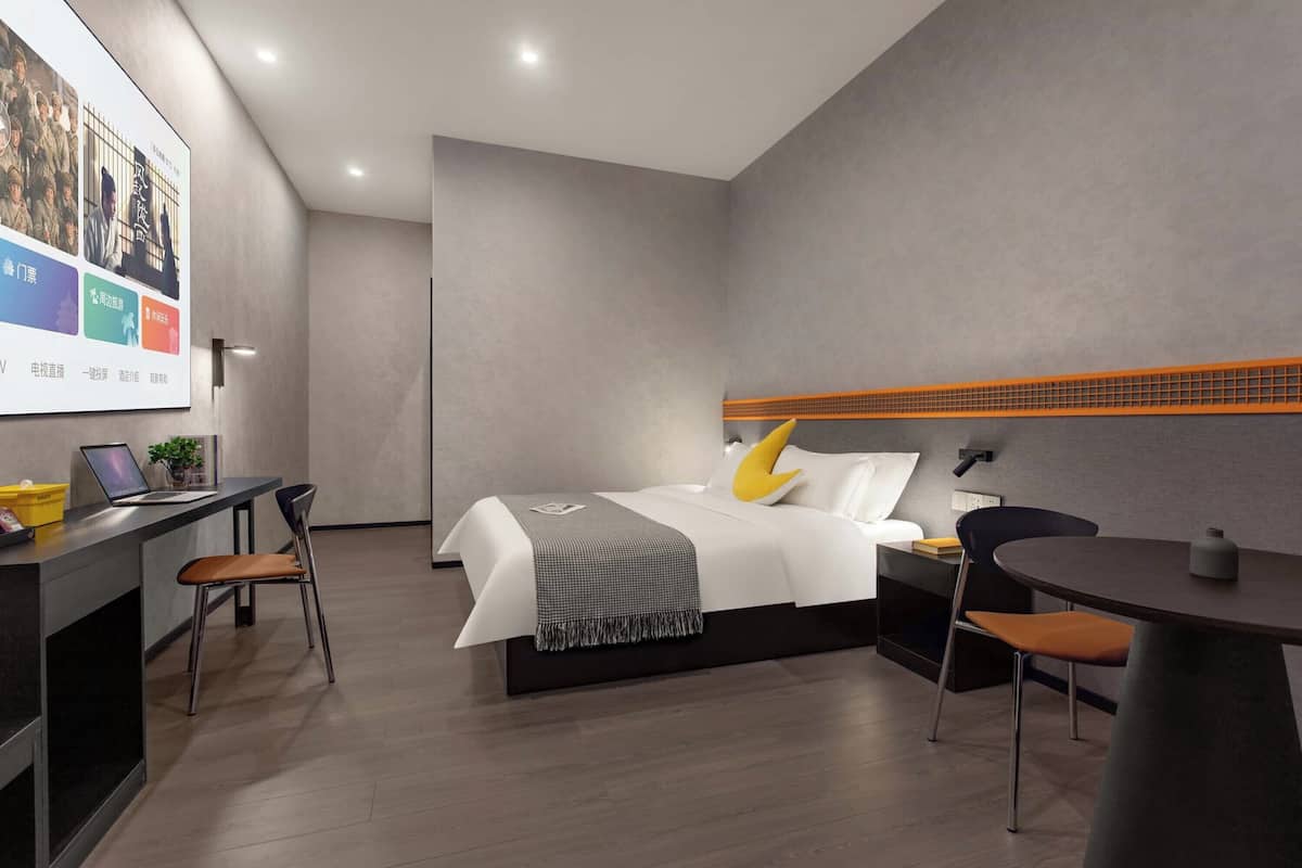 Una habitación de hotel moderna con cama, escritorio, sillas y una pequeña mesa.