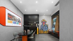 A modern meeting room with a black table, grey chairs, a large poster on the wall, and a cartoon mural. - Banana FUN Hotel (Guangzhou Beijing Road Pedestrian Street Yuexiu Park) (Guangzhou)