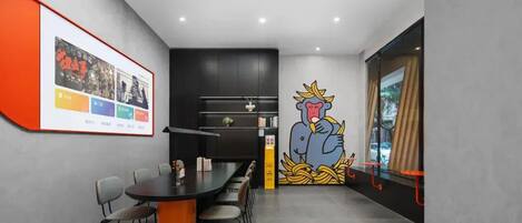 A modern meeting room with a black table, grey chairs, a large poster on the wall, and a cartoon mural.