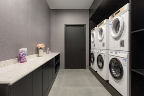 Un cuarto de lavandería con lavadora y secadora, una puerta y una encimera con un detergente y un florero.