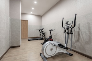 Un gimnasio con bicicletas estáticas y una cinta de correr.