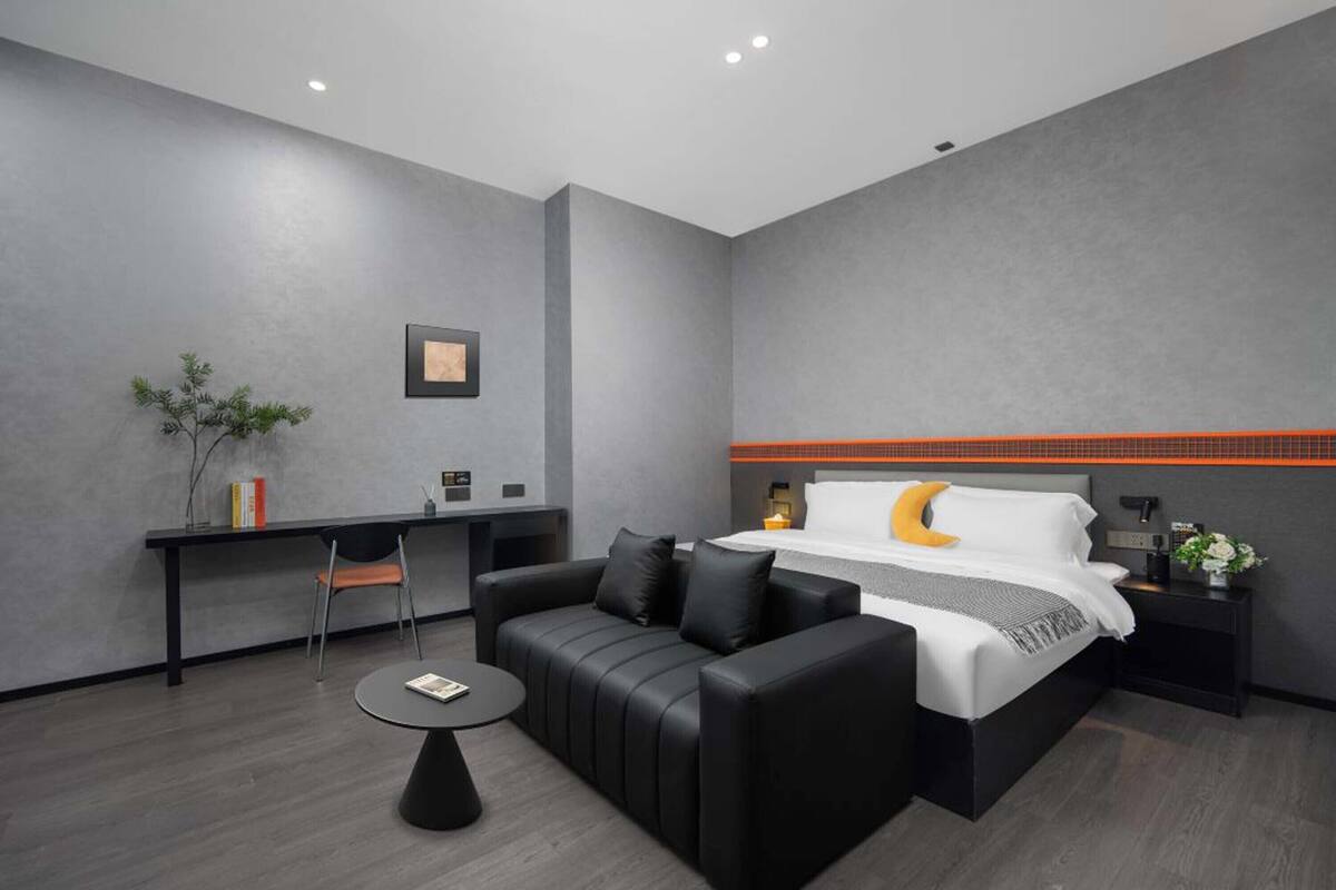Una habitación de hotel moderna con cama, sofá, escritorio y una pequeña mesa.