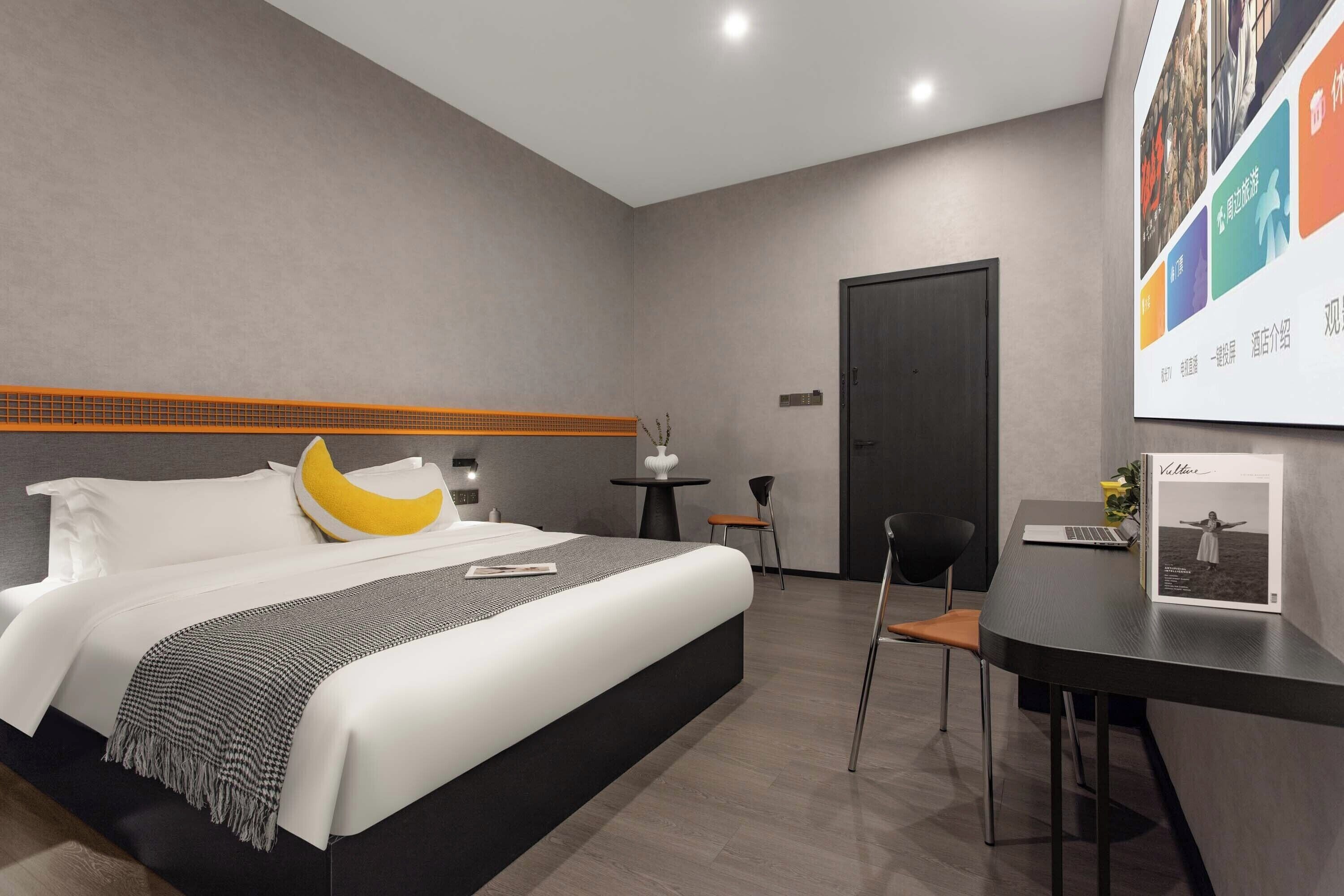 A modern hotel room with a bed, a desk, and a chair.