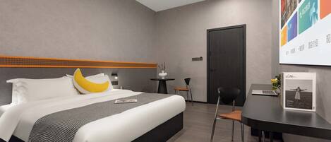 A modern hotel room with a bed, a desk, and a chair.
