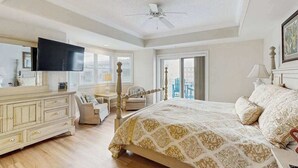 Ein Schlafzimmer mit Bett, Kommode, Fernseher und Deckenventilator.