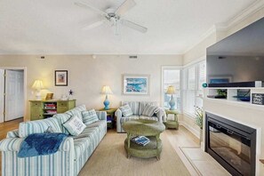 A living room with striped sofas, a fireplace, and a ceiling fan. - 4100 #201 (Ocean City)