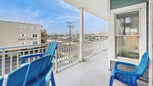 Ein Balkon mit blauen Stühlen, Blick auf den Ozean und ein Gebäude mit der Aufschrift 'Ocean Point II'.