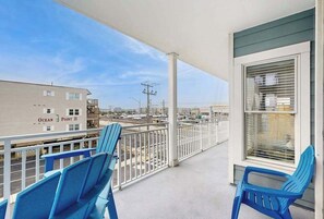 A balcony with blue chairs, a view of the ocean, and a building labeled 'Ocean Point II'. - 4100 #201 (Ocean City)