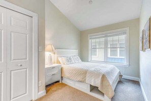 A bedroom with a bed, bedside table, lamp, window, and closet.