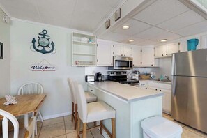 A kitchen with white cabinets, a stainless steel refrigerator, a microwave, and a coffee maker. - Renovated Sherwood West Condo | Balcony & 4 Flat-Screen TVs | 400’ to Beach (Ocean City)