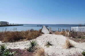 A sandy beach path leading to a pier extending into calm waters, with sparse vegetation and a clear sky. - Midtown Condo with Balcony, Gas Fireplace, Washer/Dryer, WiFi & Shared Pool (Ocean City)