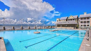 Une piscine à l’eau d’un bleu limpide, une tour de surveillance pour les sauveteurs et, au fond, un bâtiment doté de balcons.