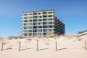 A multi-story hotel with balconies, located on a sandy beach. - Oceanfront Condo with Balcony, Central AC, Washer/Dryer, WiFi & Shared Pool (Ocean City)