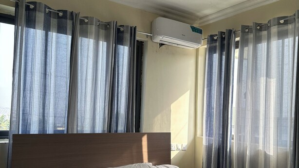 Ein Hotelzimmer mit Bett, Vorhängen, einer Klimaanlage und einem Fenster.