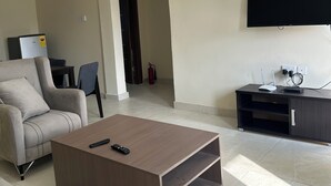 Ein modernes Wohnzimmer mit einer Couch, einem Couchtisch, einem Flachbildfernseher und einem TV-Schrank mit elektronischen Geräten.
