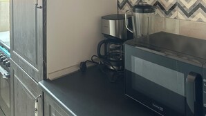 Eine Küche mit dunklen Holzschränken, einer Mikrowelle, einer Kaffeemaschine und einem Wasserkocher.